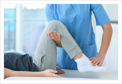 Female Physical Therapist helping stretch a patient&apos;s legs and feet